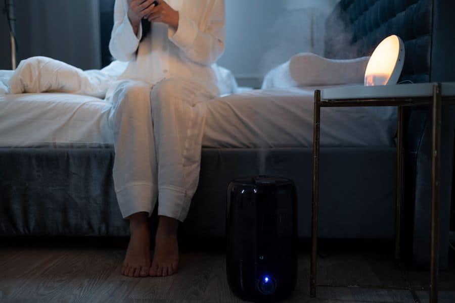 Woman using her humidifier while sitting on her bed