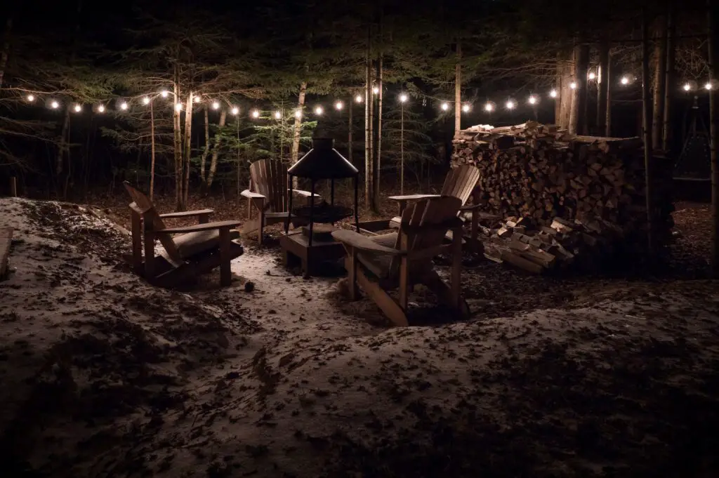 Outdoors with three chairs and a fireplace