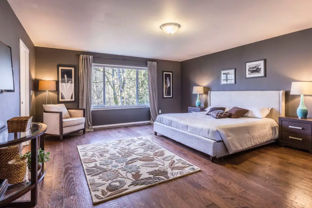 A grey toned living room with a white bed and wood floor