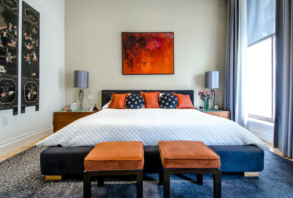 bedroom with orange and black pillows and chairs