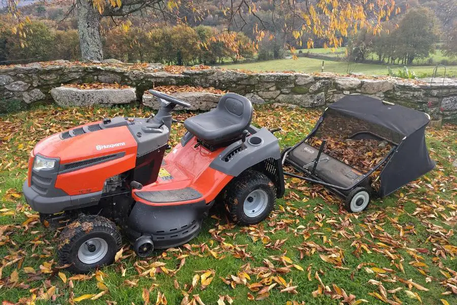 Husqvarna yth22v46 riding lawn mower collecting dried leaves in backyard