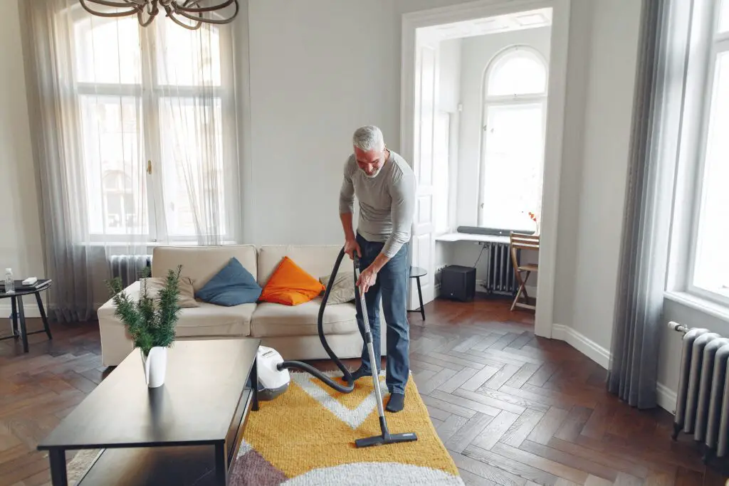 A man cleaning a carpet with a vacuum cleaner