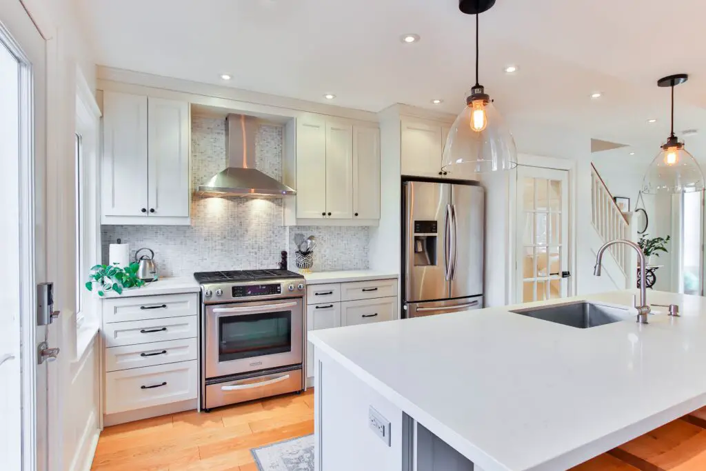 A kitchen area with orange lights and white cabinets