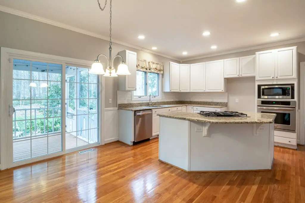 A kitchen area with cabinets and wood floor