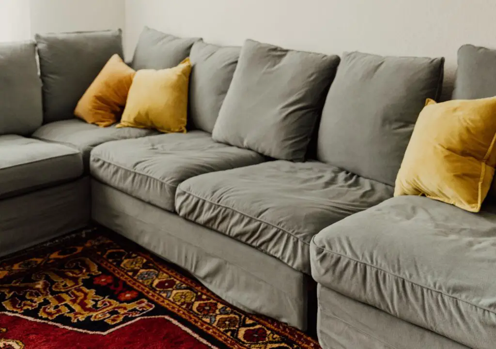 A gray sectional sofa with gray and yellow pillows