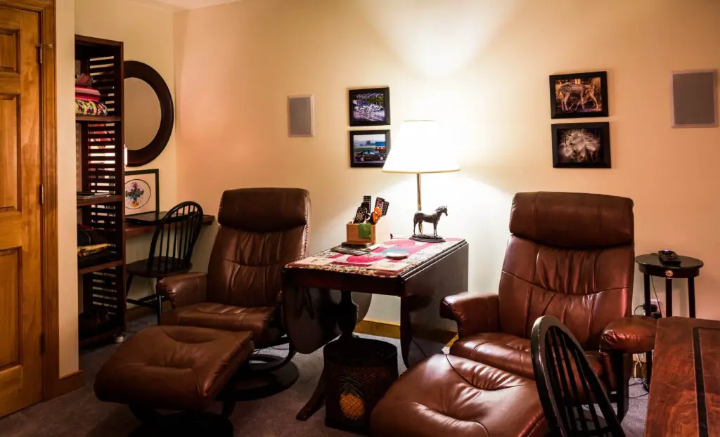 Two recliner chairs in a room with leg rest and a bright light