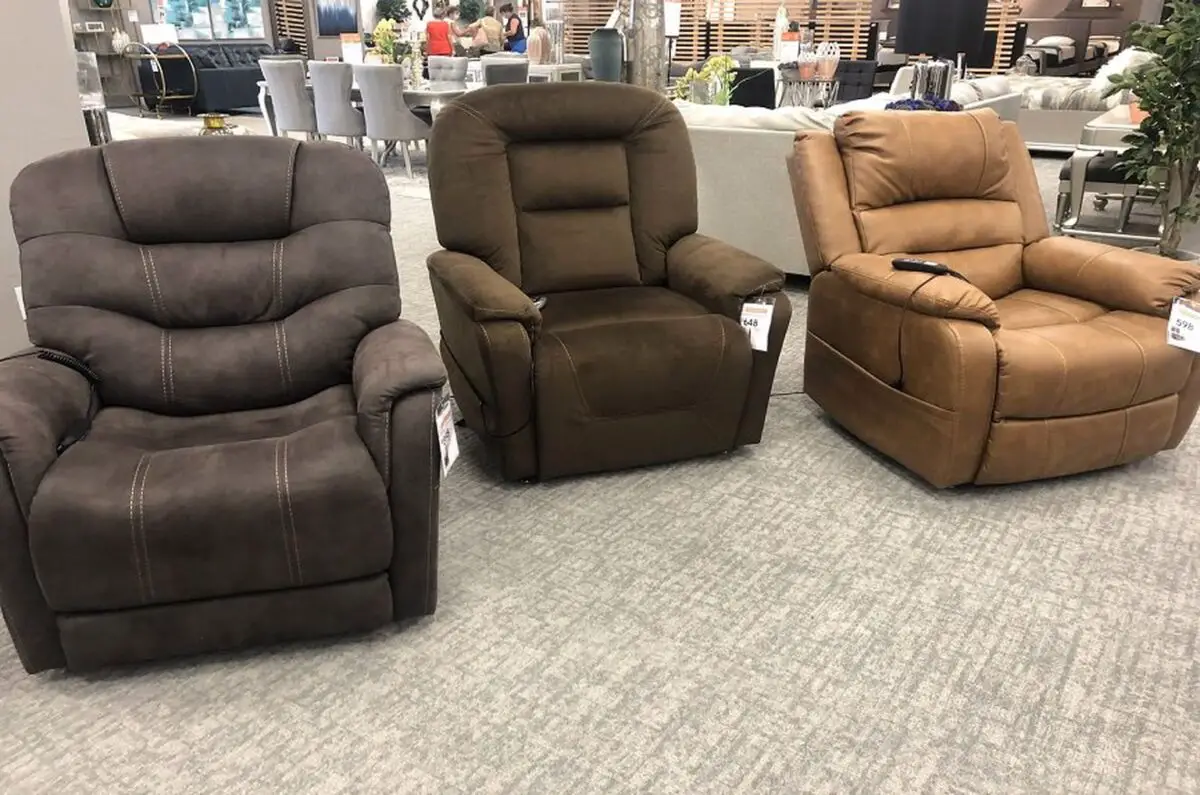 Three variations of Lazy Boy recliner chairs in colors of gray, brown and olive being displayed on department store showroom