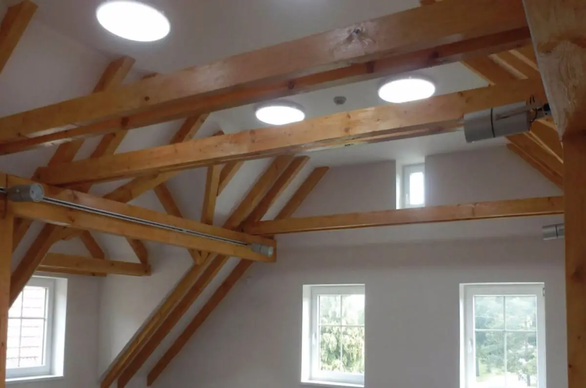 White circular light panels installed in the ceiling with wooden planks built strategically around it