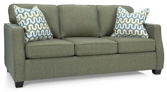 A green sofa with two throw pillows placed on a white surface