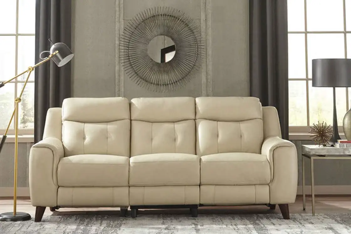 A white leather sofa beside a metal table with black lamp